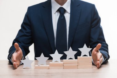 cropped view of businessman in formal wear near blocks with stars isolated on white, quality concept  clipart