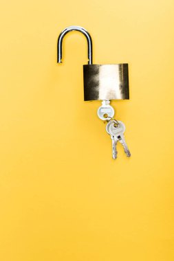 Sarı renkte izole edilmiş anahtarlarla metalik asma kilidin üst görüntüsü