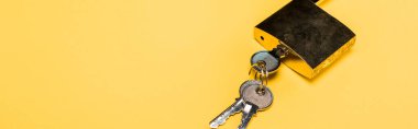 panoramic shot of metallic padlock with keys isolated on yellow clipart