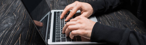 panoramic shot of hacker typing on laptop keyboard 