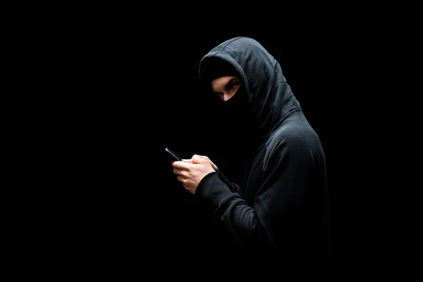 Hacker Στο Καπό Και Μάσκα Κρατώντας Smartphone Και Κοιτάζοντας Κάμερα — Φωτογραφία Αρχείου