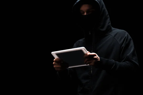 ブラックに隔離されたデジタルタブレットを使用してフードの匿名のハッカー — ストック写真