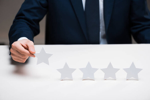 cropped view of businessman in suit holding star on grey, quality concept 