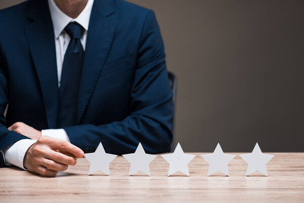 selective focus of man in suit touching star isolated on grey, quality concept 