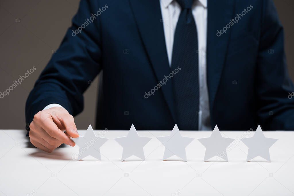 cropped view of businessman touching star isolated on grey, quality concept 