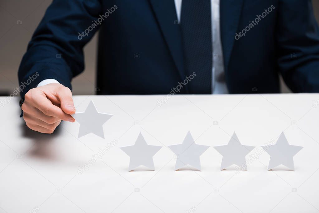 cropped view of businessman in suit holding star on grey, quality concept 