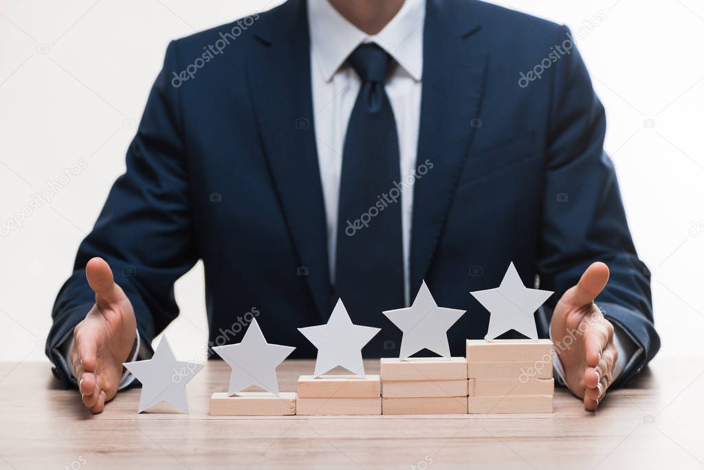 cropped view of businessman in formal wear near blocks with stars isolated on white, quality concept 