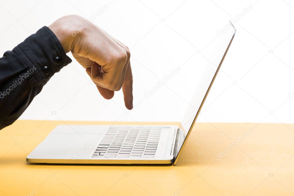 cropped view of man pointing with finger at laptop on desk isolated on white 