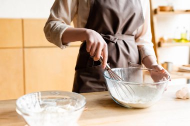 cropped view of girl holding whisk near bowl with flour clipart