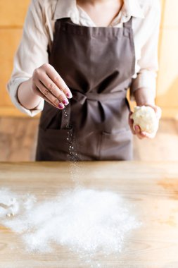 Elinde hamur tutarken masaya un döken kadın manzarası 
