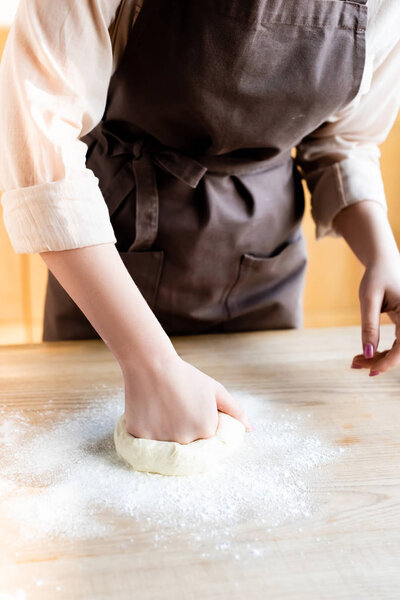 cropped view of woman kneading dough on table 