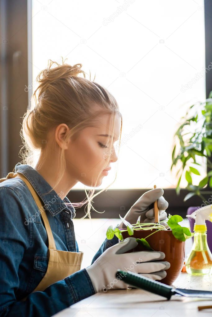 side view of girl in gloves transplanting plant in flowerpot 