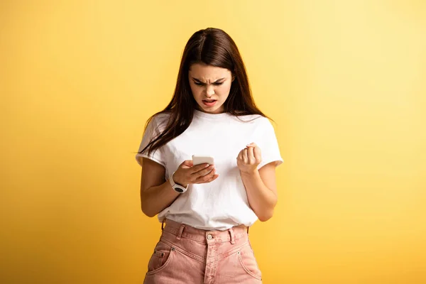 Angry Girl Holding Clenched Fist While Talking Smartphone Yellow Background — Stock Photo, Image