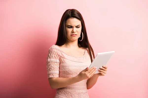 Menina Descontente Sorrir Enquanto Olha Para Tablet Digital Fundo Rosa — Fotografia de Stock