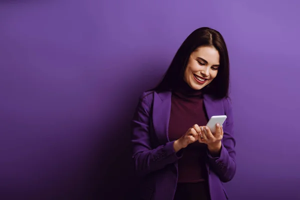 Весела Молода Жінка Посміхається Під Час Спілкування Смартфоні Фіолетовому Фоні — стокове фото