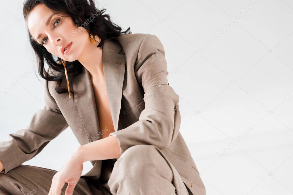 stylish woman in suit looking at camera isolated on grey