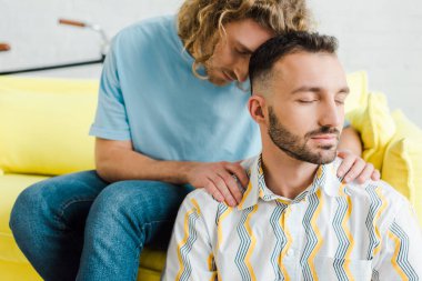 Yakışıklı, gözleri kapalı homoseksüel erkekler oturma odasında oturuyor.  