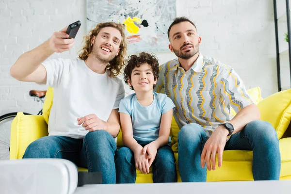快乐的同性恋父母和混血儿看电视 — 图库照片