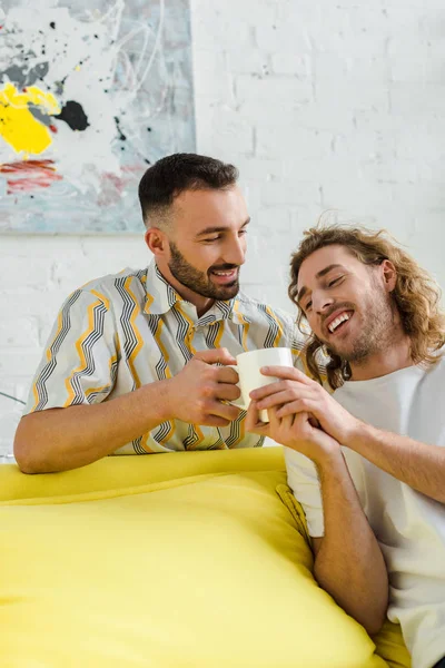 Χαμογελαστοί Ομοφυλόφιλοι Άνδρες Κρατώντας Κύπελλο Τσάι Στο Σπίτι — Φωτογραφία Αρχείου