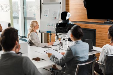 Genç çok kültürlü iş adamları konferans salonunda oturup robotlara bakıyorlar.