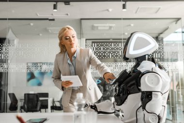 Robot kullanırken dijital tablet tutan çekici iş kadını