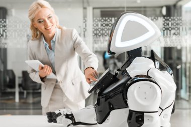 gülümseyen iş kadını dijital tableti tutarken robotu çalıştırıyor