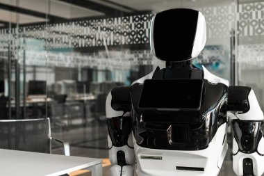 Modern ofisin konferans salonunda duran insansı robot.