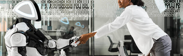 панорамный снимок африканской предпринимательницы, пожимающей руку роботу в офисе
