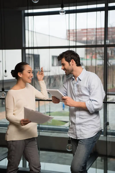 Cheerful Asian Businesswoman Holding Papers Talking Handsome Colleague Digital Tablet — Stock Photo, Image