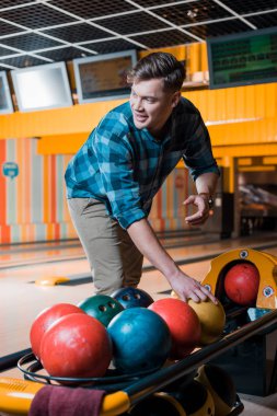 Yakışıklı gülümseyen adam bowling kulübünde bowling topu alıyor.