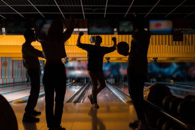 dark silhouettes of four friends playing bowling in bowling club clipart