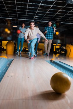 Yakışıklı genç adam, çok kültürlü arkadaşlarının yakınındaki Skittle sokağına bowling topu atıyor.