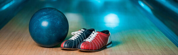 panoramic shot of bowling shoes and ball on skittle alley in bowling club