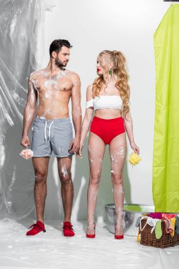 sexy pin up girl holding wet sponge with soap near shirtless man on white  clipart
