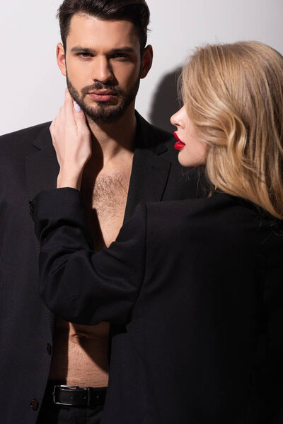 attractive woman with red lips touching bearded man on white