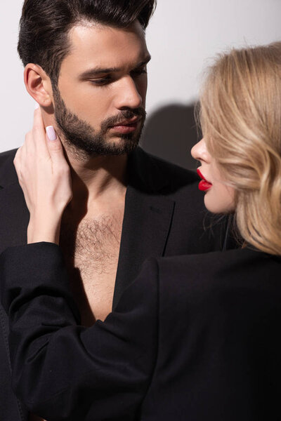 attractive woman with red lips touching handsome man on white