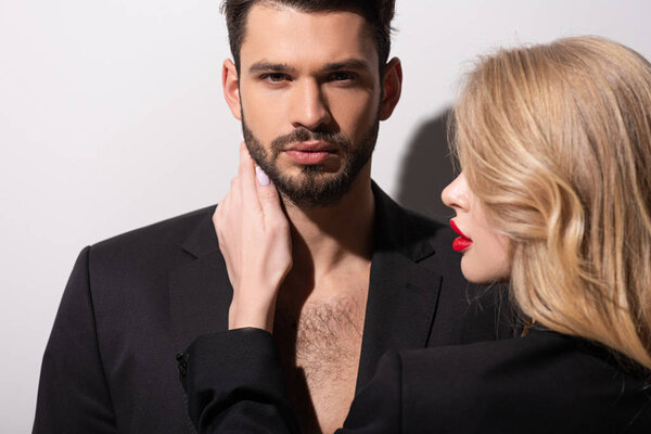 attractive woman with red lips touching handsome boyfriend on white