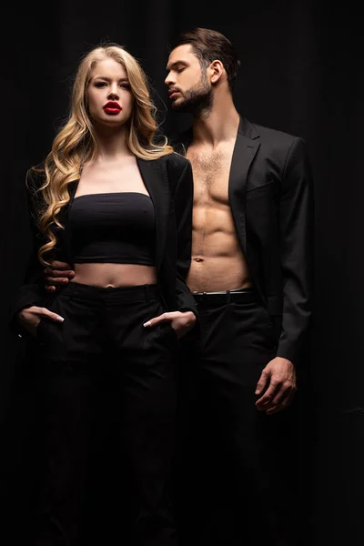 Bonito Homem Olhando Elegante Mulher Com Mãos Bolsos Isolados Preto — Fotografia de Stock