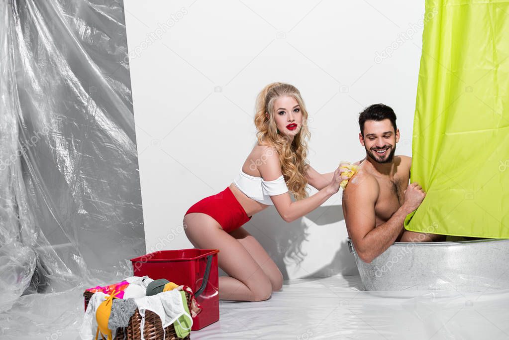 sexy pin up woman washing man with sponge on white