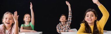 panoramic shot of schoolchildren with raised hands isolated on black  clipart