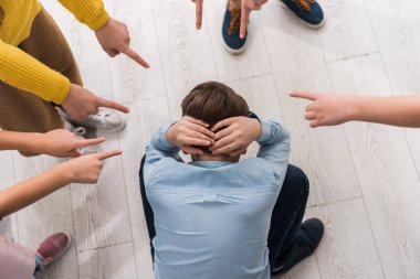 top view of cruel schoolkids pointing with fingers at bullied classmate  clipart