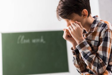 Zorbalık ve depresyondaki okul çocuğu sınıfta yüzünü kapatıyor. 