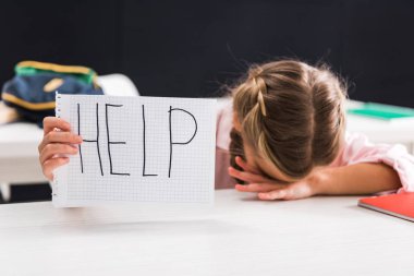 Harflerle, zorbalıklarla dolu bir kağıt tutan liseli kız.