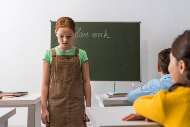 Sınıf arkadaşlarının masalarında oturan üzgün öğrencilerin seçici odak noktası. 