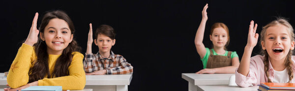 panoramic shot of schoolkids with raised hands isolated on black 