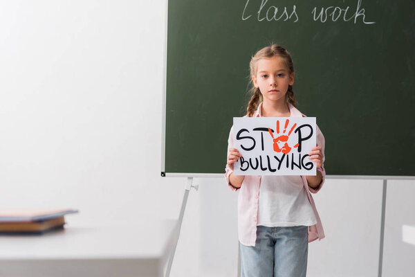 selective focus of schoolkid holding placard with stop bullying lettering 