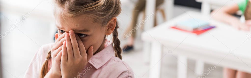 panoramic shot of upset schoolkid crying in classroom, bullying concept 