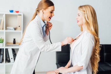 Mutlu ve seksi hemşire klinikteki genç bayanı muayene ediyor. 