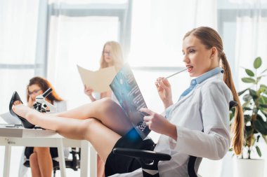 Fen dergisi okuyan, kadınların yanında oturan ve kalem yiyen seksi hemşirelerin seçici odağı. 