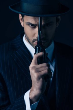 Koyu mavi suratlı gangsterin silahı var.